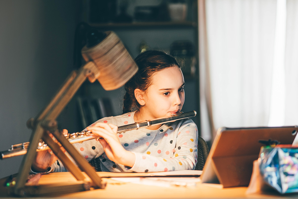 A young girl practicing online music lessons.